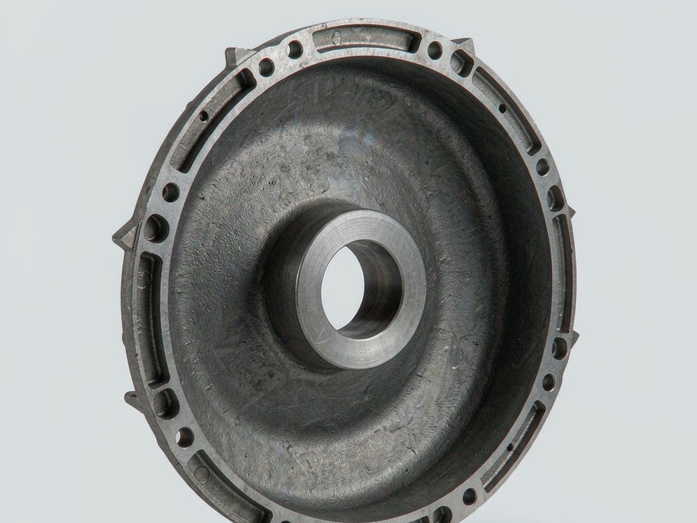 Round motor end cover casting with a ring of bolt holes and a central bearing boss