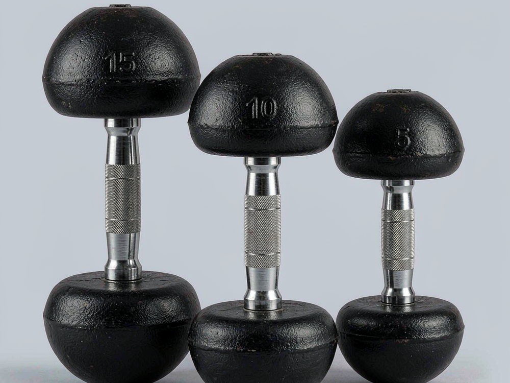 Three round-head cast iron dumbbells of increasing size in a row