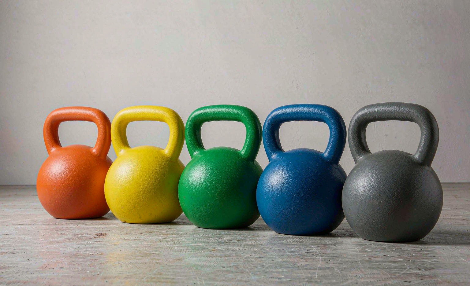 Row of five competition kettlebells in different colours but the same body size