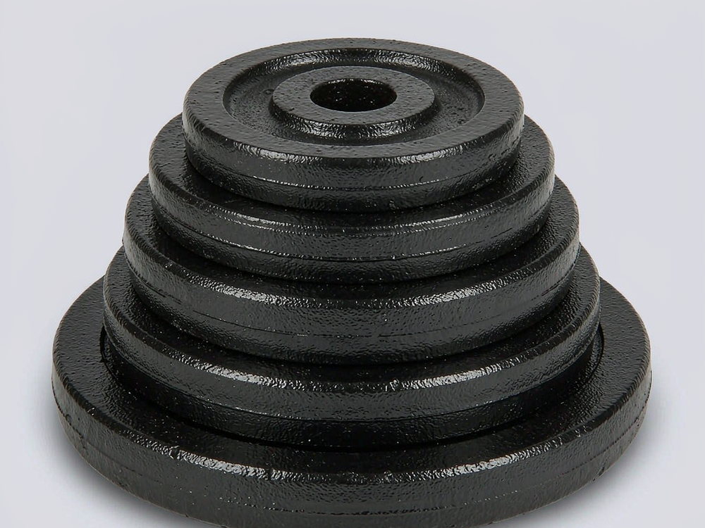 Stack of five cast iron barbell plates of decreasing diameter