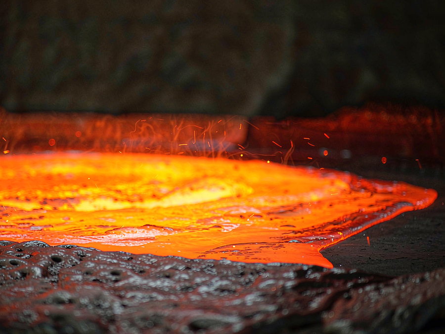 Surface of molten grey iron glowing orange in a foundry